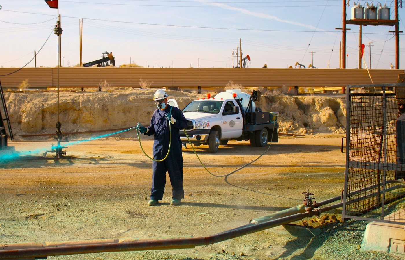 Technician performing vegetation treatment in an industrial environment
